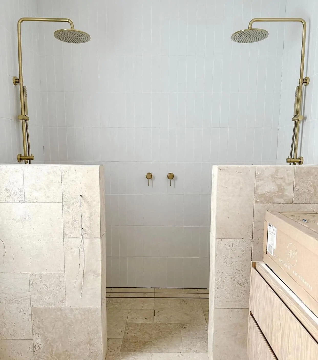 A modern bathroom with a freestanding bathtub, dark travertine wall tiles, and a rainfall shower.