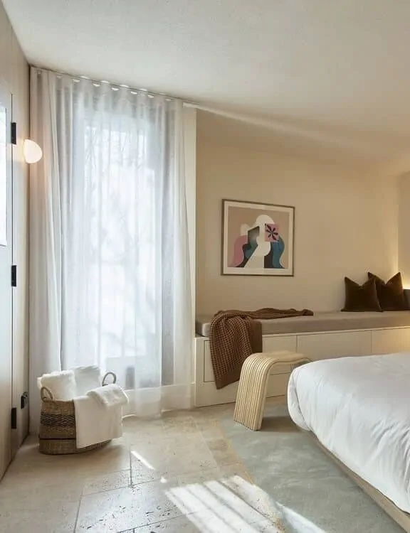 A cozy bedroom with travertine flooring, soft lighting, and neutral decor.