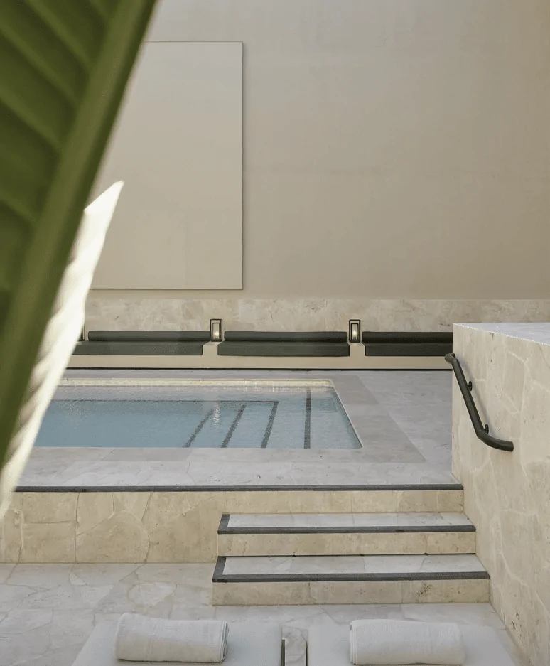 A luxurious spa-style pool area with travertine steps, built-in seating, and elegant minimalist architecture.